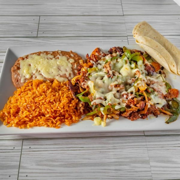 El Sazon Mexican Grill's fajita plate with rice, refried beans, and tortillas on a white platter.