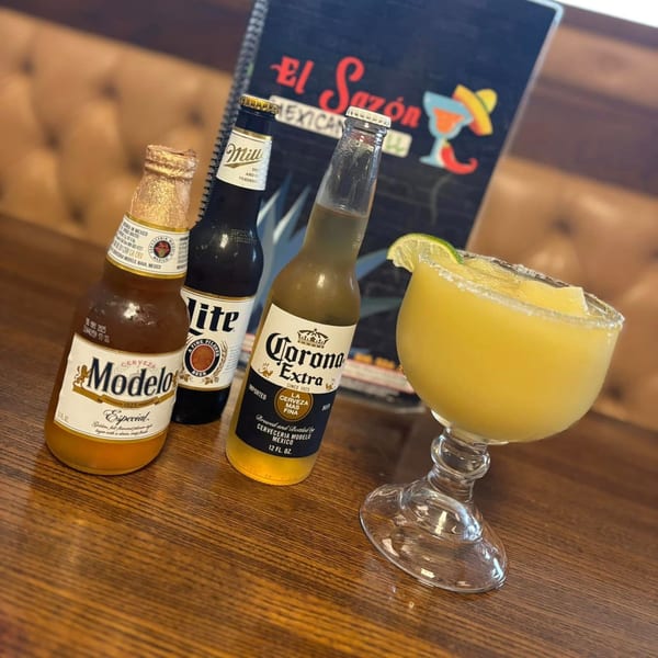 Modelo, Miller Lite, and Corona beers with a frozen margarita on a wooden table at El Sazon Mexican Grill.