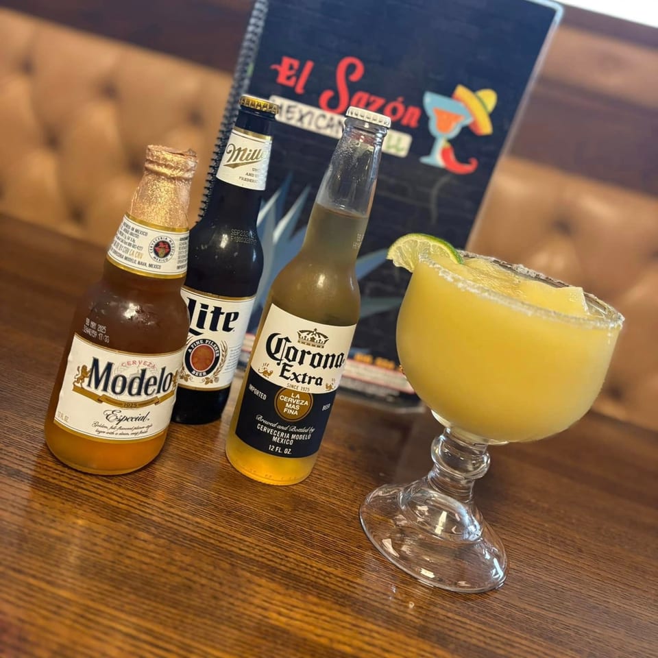 Modelo, Miller Lite, and Corona beers with a frozen margarita on a wooden table at El Sazon Mexican Grill.
